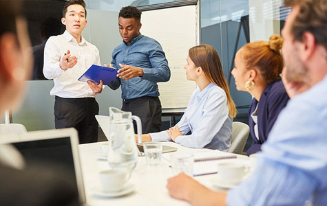 A group of individuals in a boardroom presenting on how to integrate employee scheduling software and time tracking software