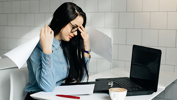 Stressed Female Manager with Papers and Laptop