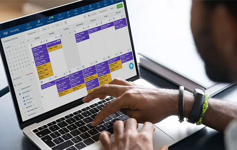 overhead shot of a person typing on a laptop accessing their time tracking software