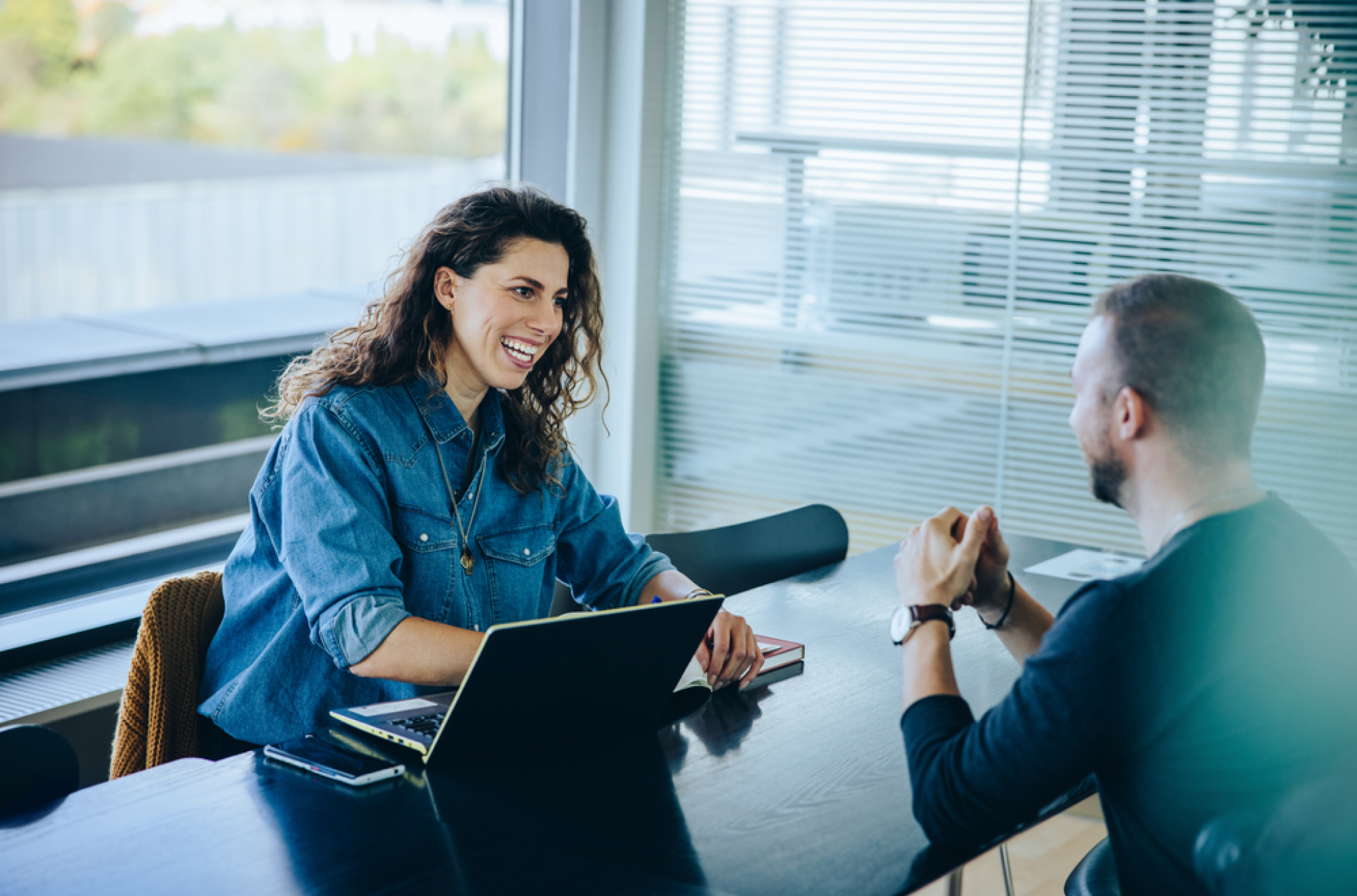 An HR professional woman behind her laptop having a face to face conversation with an employee about the types of leave management and what his leave will classify as