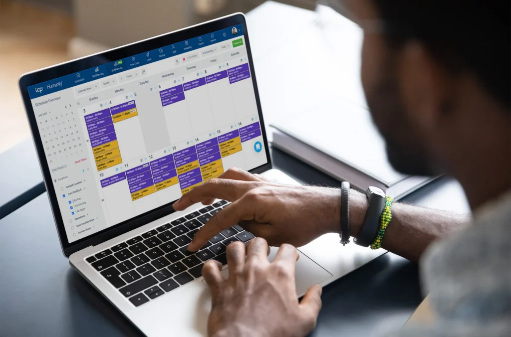 Someone overlooking their computer screen with scheduling software on display, visualizing the employee scheduling software buyer's guide as they're walking through the steps of a demo