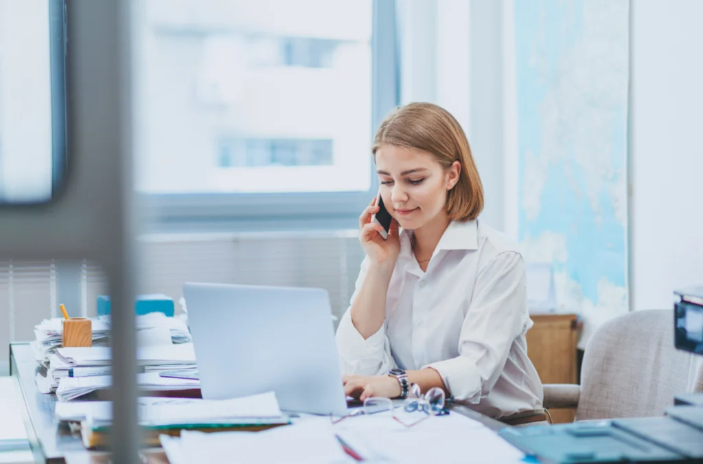 Woman in a white button down looking down at her computer, contemplating her employee time tracking guide and the next decision to make