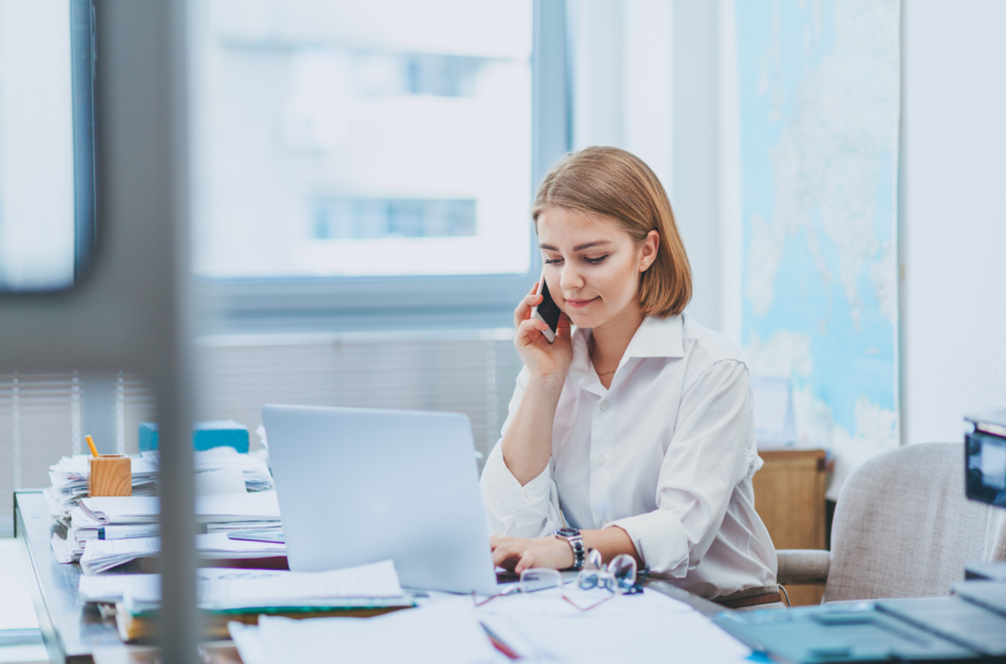 Woman in a white button down looking down at her computer, contemplating her employee time tracking guide and the next decision to make