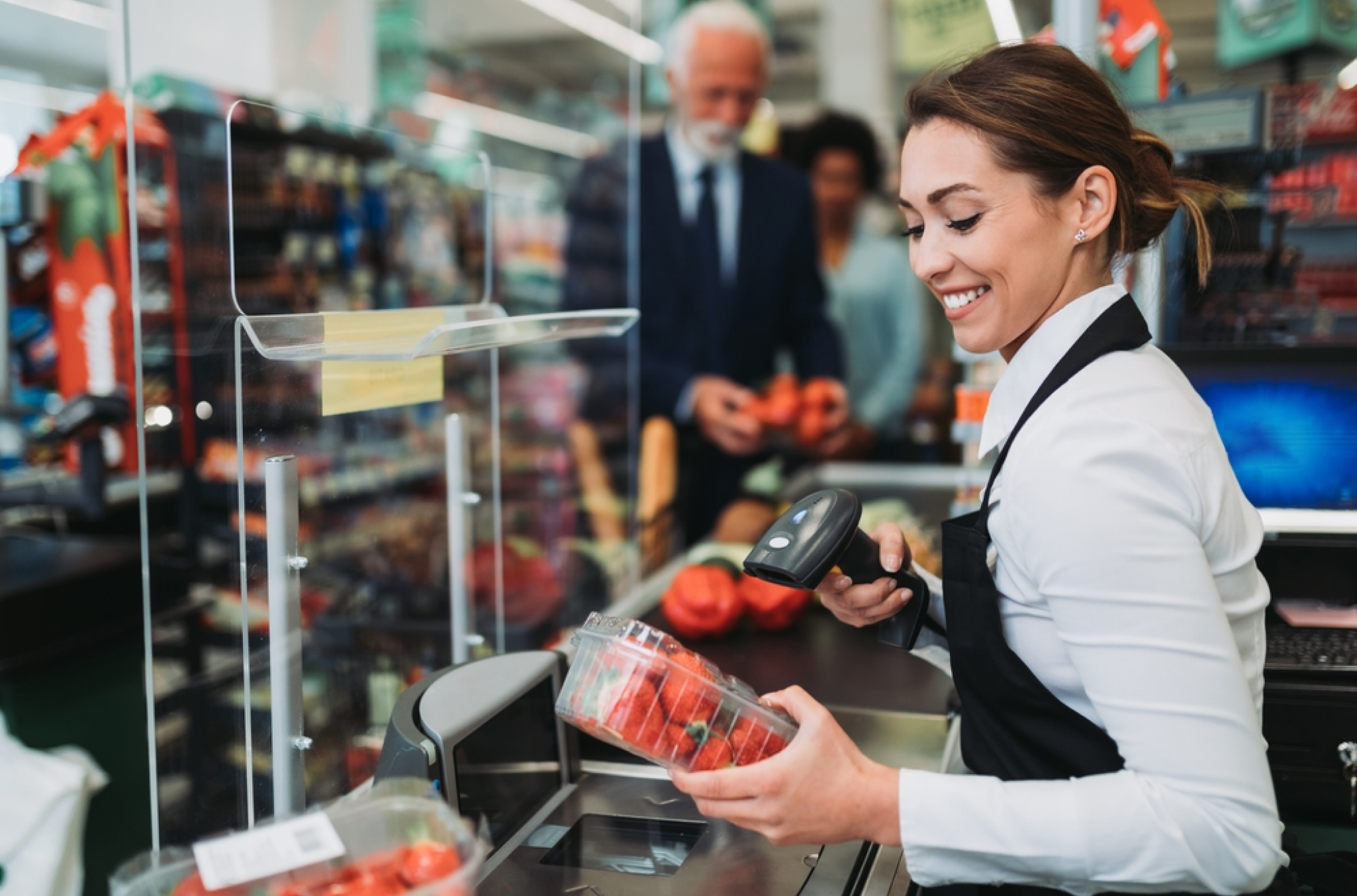 A woman as a grocery store checkout clerk being satisfied because of the employee scheduling in retail considerations from her organization