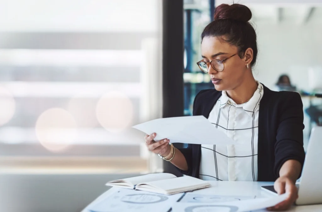 A woman reviewing her manual payroll sheets with lots of payroll errors on them, as she looked frustrated by the effects of manual payroll