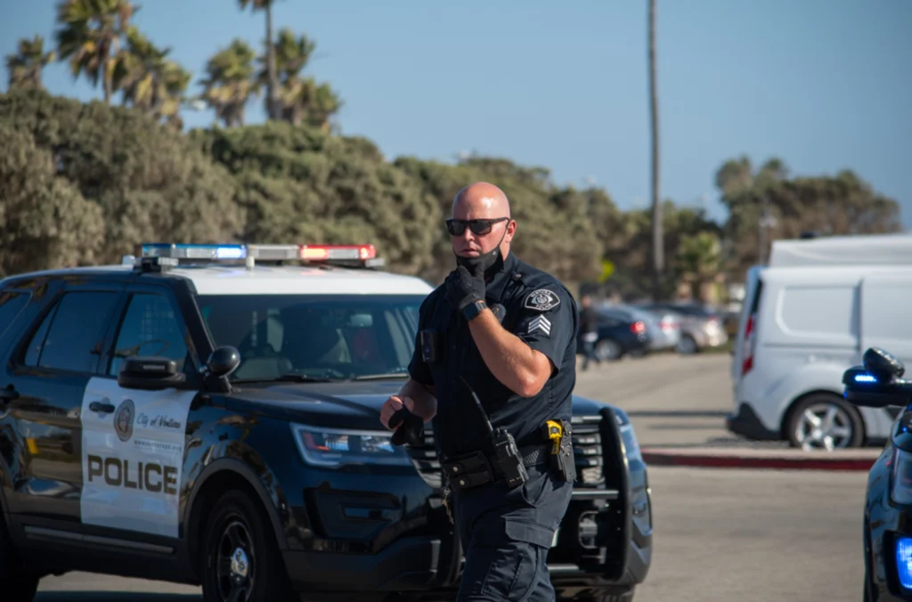 Police officer on the scene speaking into his dispatch speaker, arriving punctually because he is on a rotating shift