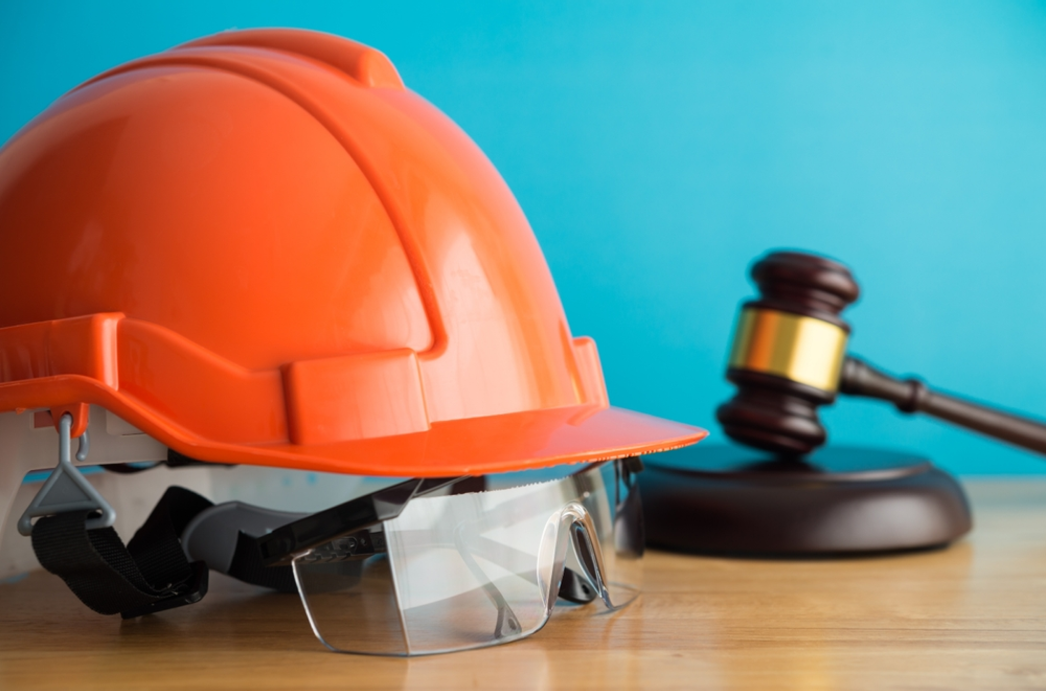 An orange hard hat and a gavel on a table, to demonstrate the mixed benefactors and subjects of the Fair Labor Standards Act (FLSA)