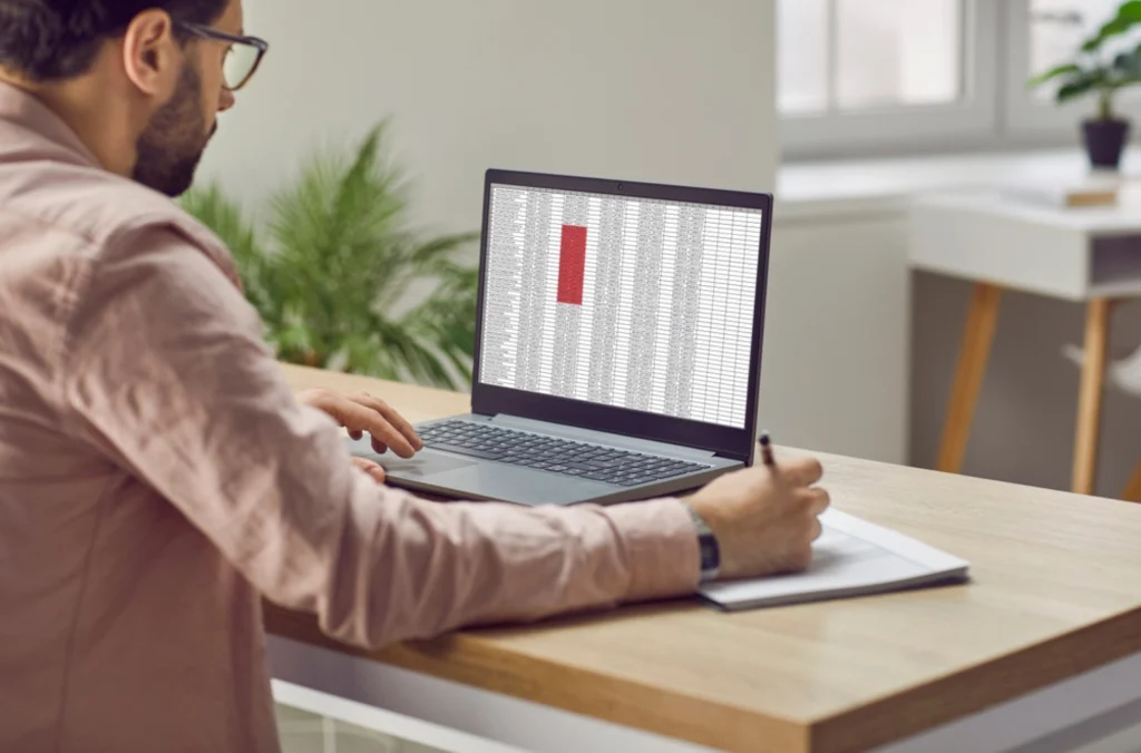 Side angle image of a business person sitting in front of computers, looking at how to upgrade online timesheet software