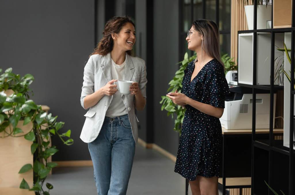 Two female employees exchanging over a coffee break, to symbolize employee break laws being complied with