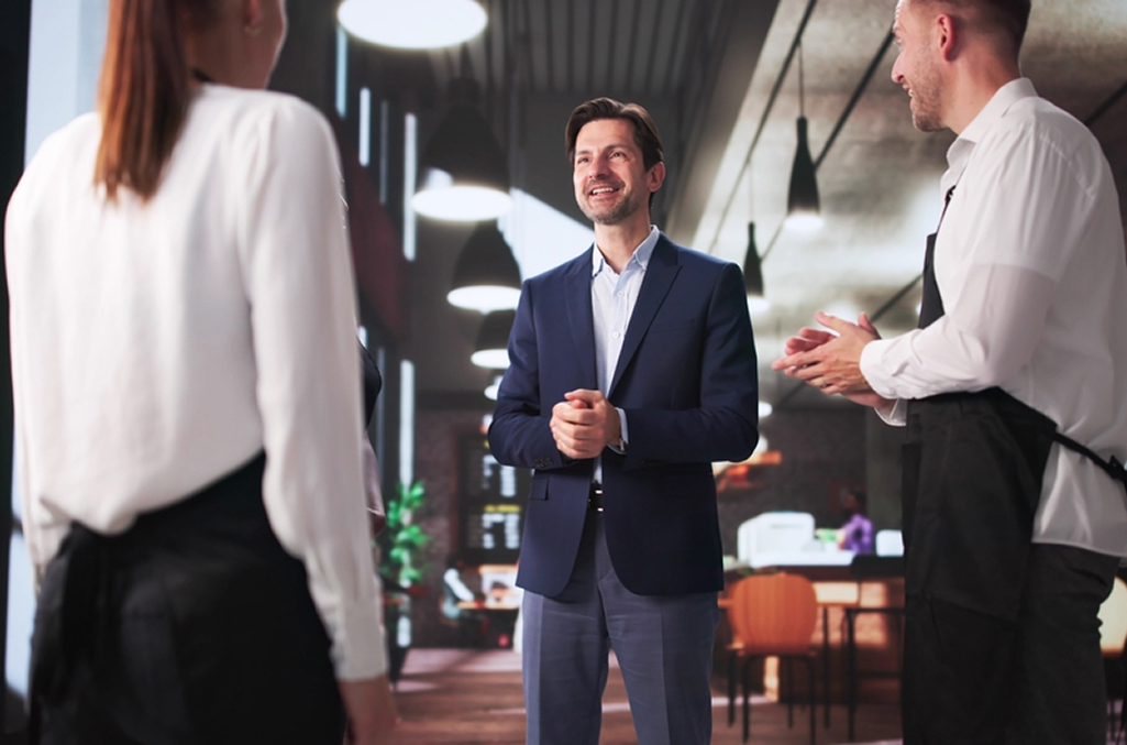 A restaurant manager discussing with two employees the shifts ahead for the week, to symbolize how to improve time tracking in food and beverage