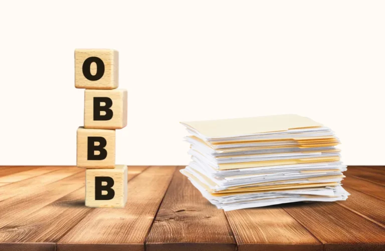 A stack of judicial paperwork on a table next to a stack of blocks that spells OBBB vertically, to represent content about the One Big Beautiful Bill Act