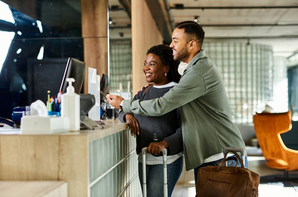 Couple checking into front desk with luggage