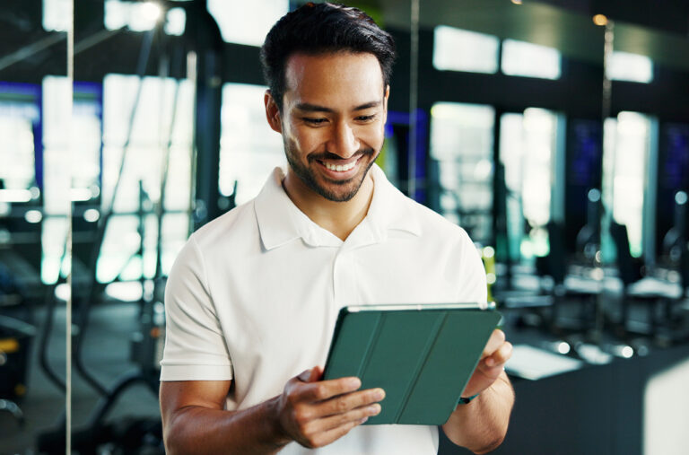 A gym manager looking at employee timecards on a tablet, to illustrate how to improve time tracking in entertainment and recreation