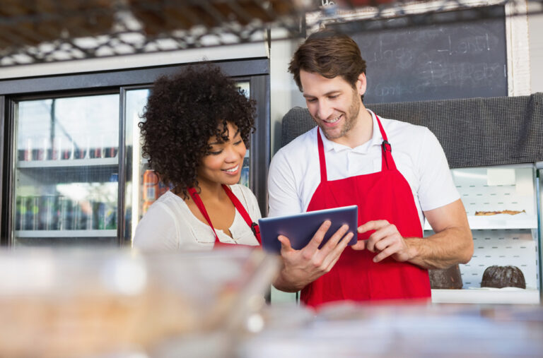 Two workers, male and female, interacting over a tablet software for time tracking in retail